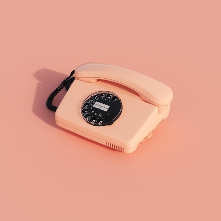 Rosafarbenes Telefon mit Wählscheibe auf rosafarbenem Hintergrund.